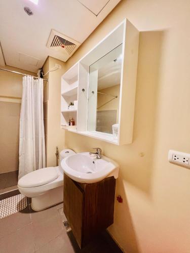 a bathroom with a sink and a toilet and a mirror at Avida Towers Atria in Iloilo City