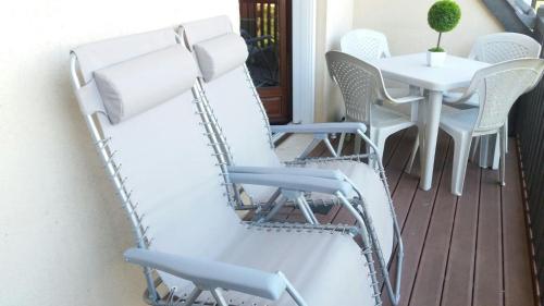 d'un balcon avec des chaises blanches et une table. dans l'établissement Confortable 2 pièces calme à 200 m plage wifi, à Cabourg