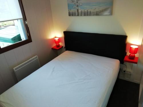 - une chambre avec un lit et 2 bougies rouges sur 2 tables dans l'établissement Confortable 2 pièces calme à 200 m plage wifi, à Cabourg