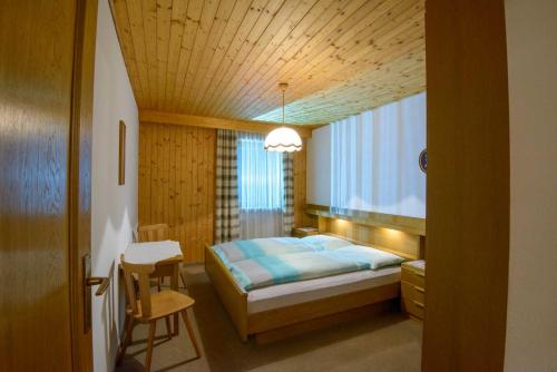 a bedroom with a bed and a table and a window at Appartement Alpenblick in Valdaora