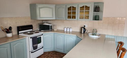 a kitchen with blue cabinets and white appliances at My Happy Place in Jongensfontein