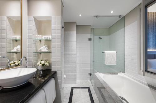 a bathroom with a tub and a sink and a shower at Paradox Sydney in Sydney