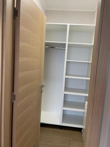 a closet with white shelves and a wooden door at Moaline Apartments, free parking in Sarajevo