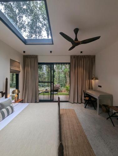 1 dormitorio con ventilador de techo, 1 cama y 1 mesa en Earthsong Luxury Pool Villa by Luxunlock Private Villas, en Suntikoppa