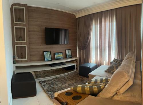 a living room with a couch and a tv at Apto 3 Suítes e Garagem Dupla Itapema Meia Praia em Ótima Localização in Itapema
