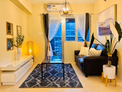 a living room with a black couch and a glass table at Avida Towers Atria in Iloilo City