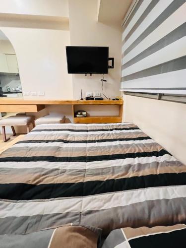 a bedroom with a bed and a desk with a television at Avida Towers Atria in Iloilo City