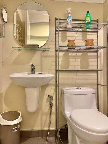 a bathroom with a toilet and a sink and a mirror at Avida Towers Atria in Iloilo City