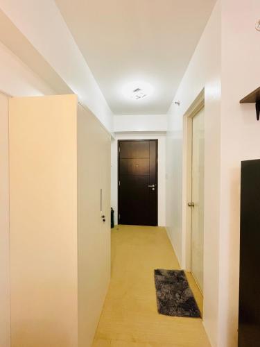a hallway with a black door and a rug at Avida Towers Atria in Iloilo City