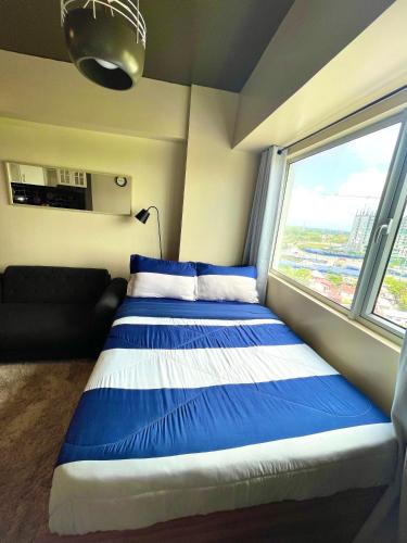 a bedroom with a blue and white bed and a window at Avida Towers Atria in Iloilo City
