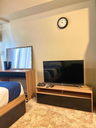 a bedroom with a television and a clock on the wall at Avida Towers Atria in Iloilo City