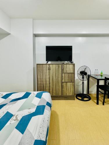 a bedroom with a tv and a bed and a table at Avida Towers Atria in Iloilo City
