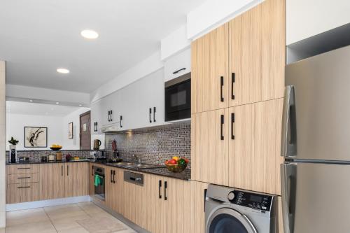 a kitchen with wooden cabinets and a washer and dryer at Somerset West Bay Doha in Doha