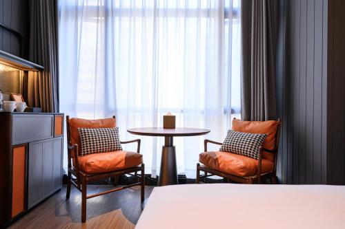 a hotel room with a table and two chairs at UrCove by HYATT Shantou Zhugang New Town in Shantou