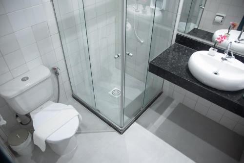 a bathroom with a shower and a toilet and a sink at Hotel Praia do Morro in Guarapari