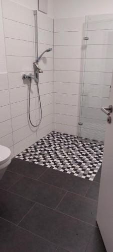 a bathroom with a shower with a black and white tile floor at Panoramalounge Moselblick - Toplage in Traben-Trarbach