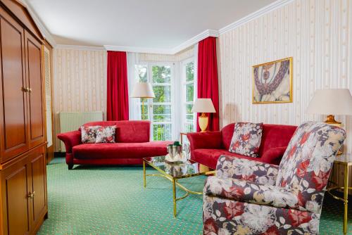 a living room with a red couch and a chair at Hotel am Schlosspark in Gotha