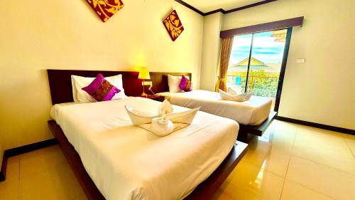 a hotel room with two beds and a window at KS Residence Patong in Patong Beach