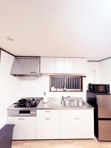 a white kitchen with a sink and a stove at 谷町線歩く5分 梅田駅まで8分 Wi-Fiあり 今年リフォーム済み in Osaka