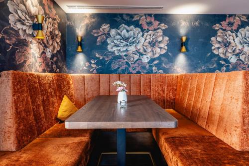 a table in a booth at a restaurant with a floral wallpaper at Hotel am Schlosspark in Gotha