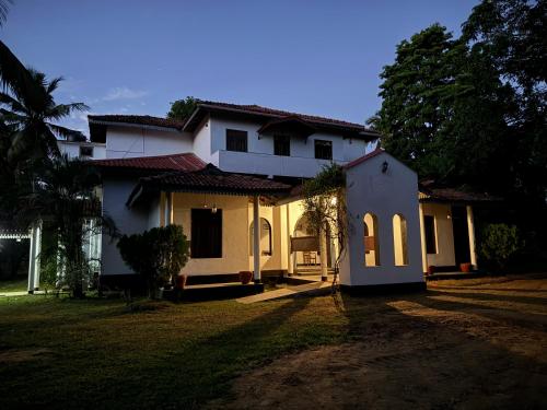a white house with a yard in front of it at Illukawela Walauwa in Embilipitiya