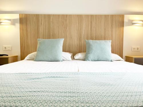 a large bed with two blue pillows on it at Bungalows Los Almendros - Exclusive Vacation Club in Playa del Ingles