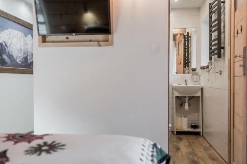 a bedroom with a bed and a sink and a television at Willa Belmont in Zakopane