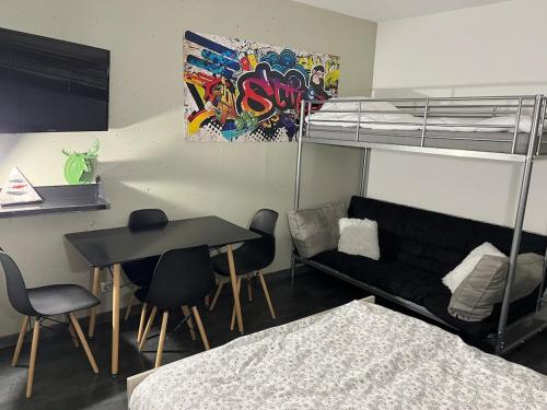 Cette chambre comprend des lits superposés, une table et un canapé. dans l'établissement Charmand studio auron, à Saint-Étienne-de-Tinée