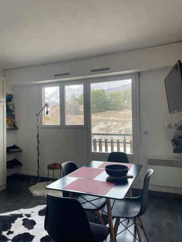 une salle à manger avec une table et des chaises et une fenêtre dans l'établissement Charmand studio auron, à Saint-Étienne-de-Tinée