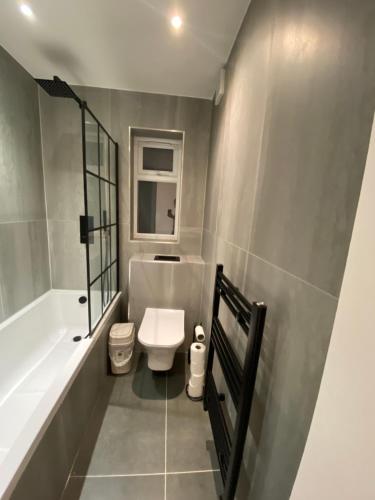 a bathroom with a toilet and a tub and a sink at Winter double bedroom in Stone Grove