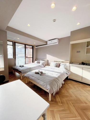 two beds in a room with wooden floors and windows at 浅草スカイガーデンホテル in Tokyo