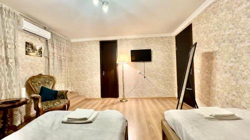 a room with two beds and a chair and a television at Old city Apartment 1 in Tbilisi City
