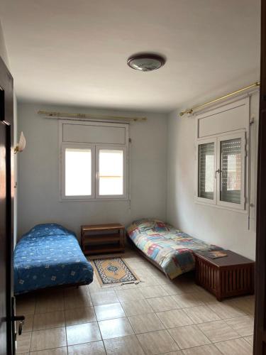 Tamraght OuzdarにあるJamal's Holiday apartementsのベッド2台と窓2つが備わる客室です。