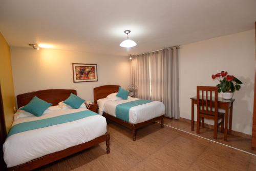a hotel room with two beds and a table and a chair at Hotel Palmas Reales in Trujillo