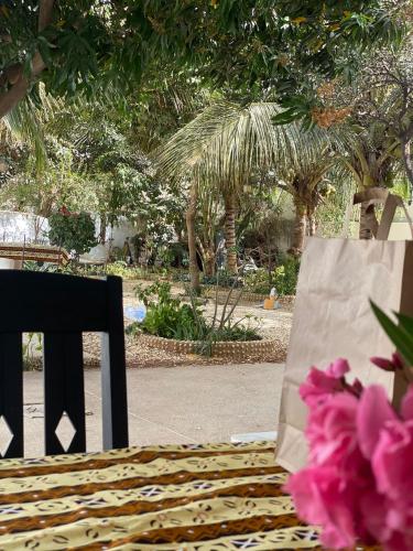 a shopping bag sitting next to a bench with pink flowers at Zion in Ngaparou
