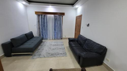 a living room with a black leather couch and a rug at Apartamentos en Punta Cana in Punta Cana
