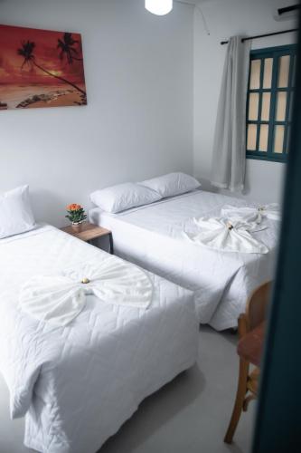 two beds sitting next to each other in a room at Hotel Praia do Morro in Guarapari