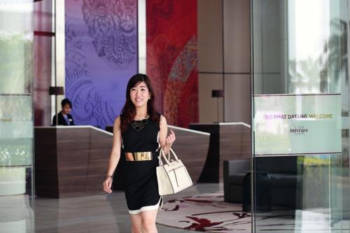 a woman in a black dress walking in a lobby at Mercure Karawang in Karawang
