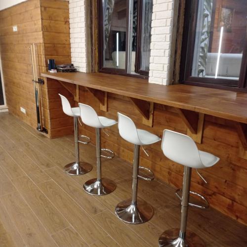 a bar with three white chairs in front of a counter at Dom Parlinek agroturtstyka wędkowanie sauna jacuzzi in Dąbrowa