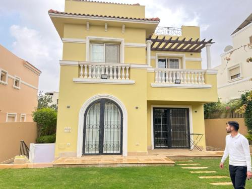 um homem a andar em frente a uma casa amarela em Compound Hyde park em New cairo