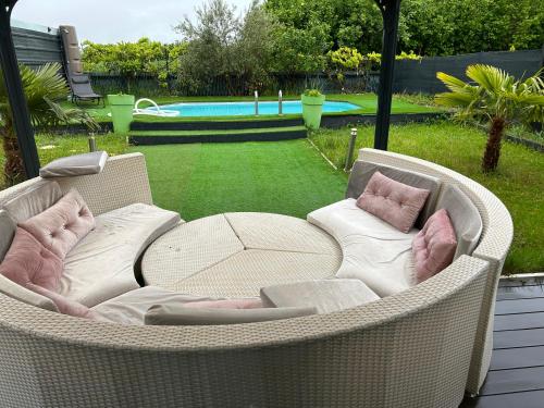 une chaise en osier avec deux oreillers et une table dans l'établissement Maison entière, à Cébazat