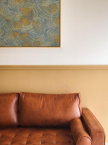 a brown leather couch in a room with a painting at Mid Valley Southkey Mosaic Cozy Suite at Johor Bahru in Johor Bahru
