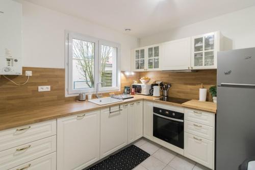 une cuisine avec des armoires blanches et des appareils électroménagers blancs dans l'établissement Chez Maxou - 3 ēpis Jardin Clos-Garage, à Revel