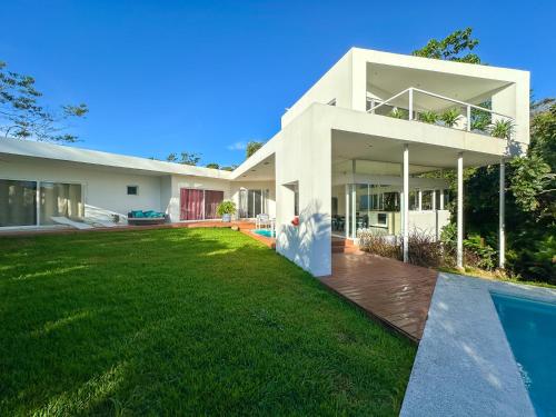 a white house with a yard and a swimming pool at Ocean View Villa 2min to beach - Casa Cantini in Montezuma