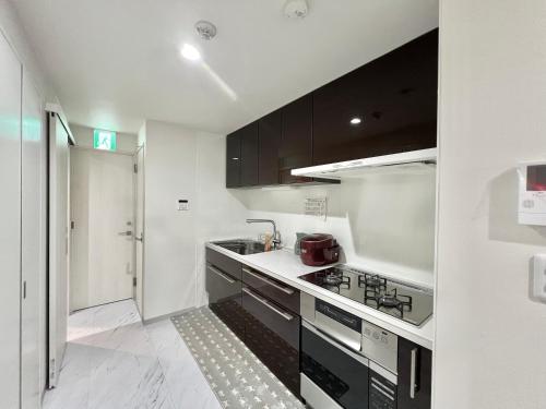 a kitchen with black and white cabinets and a sink at Sugamo-4F in Tokyo