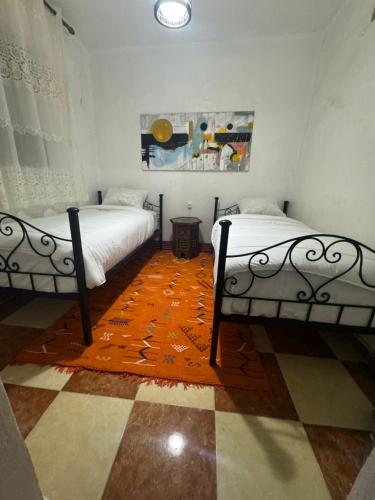 two beds in a room with a orange rug at Bleu home in Chefchaouene