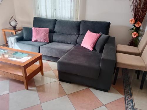 a living room with a black couch and pink pillows at Casa La Montaña in Las Navas del Marqués