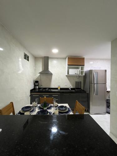 a kitchen with a table with chairs and a refrigerator at Sobrado para até 16 pessoas px ao centro in Porto De Galinhas