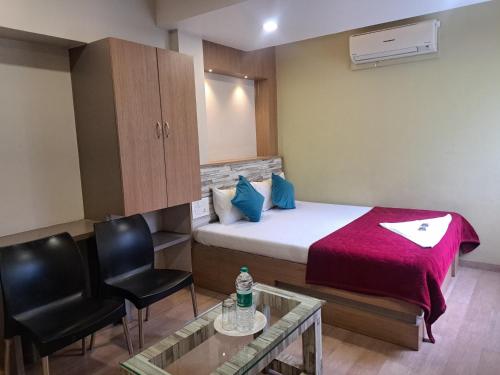 a small room with a bed and a table and chairs at Central Inn, Kolhapur in Kolhapur
