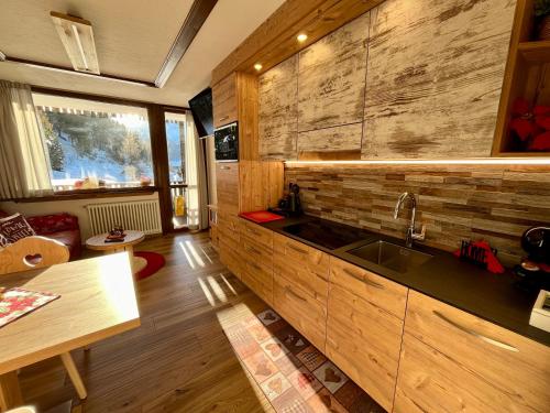 kuchnia ze zlewem i drewnianą ścianą w obiekcie Home, sweet home w Livigno
